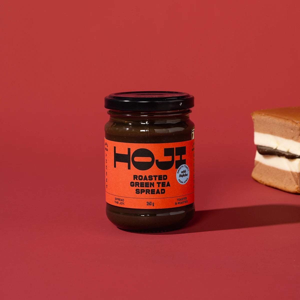 Jar of HOJI roasted green tea spread on a red background
