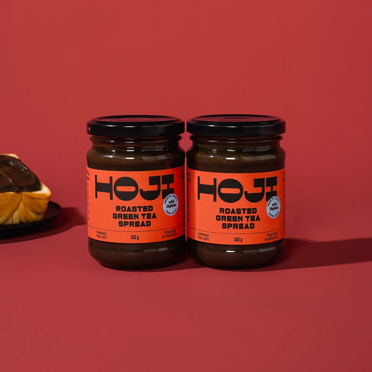 Two jars of HOJI Roasted Green Tea Spread on a red background